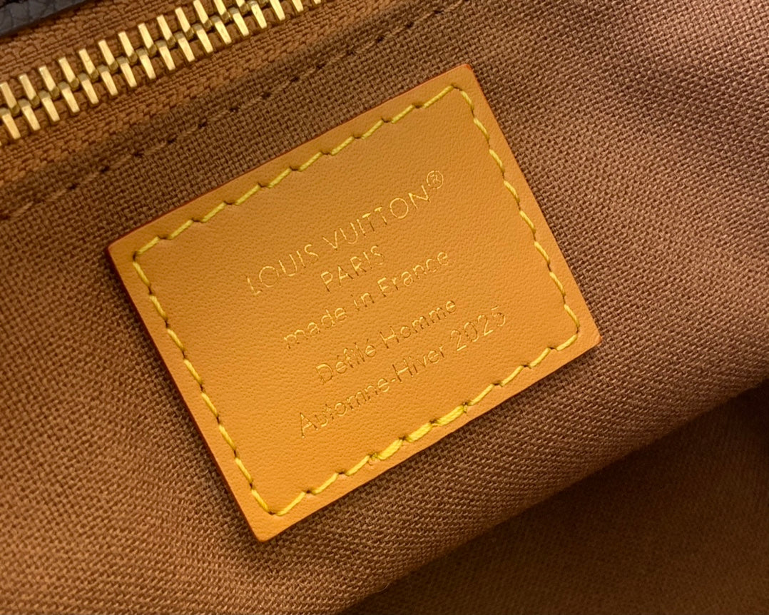 Leather interior tag with Louis Vuitton text and gold stitching.