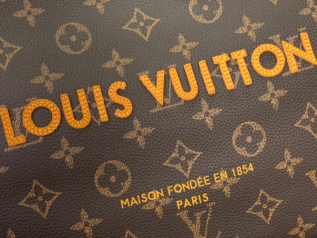 Louis Vuitton monogram canvas close-up with gold lettering and accents
