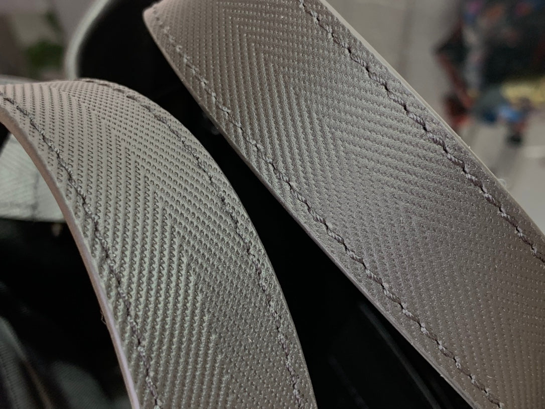 Dark leather strap edge with visible stitching on tote bag