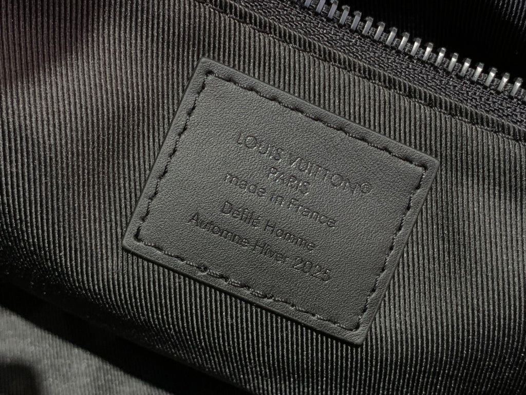 Louis Vuitton interior leather label on dark fabric, stitched text panel