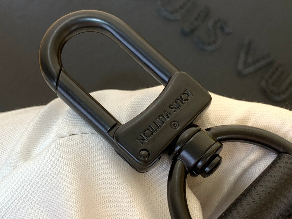 Dark leather key fob with metal D-ring hardware attached to a bag