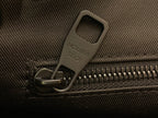 Close-up of zipper pull on textured fabric with embossed logo tab