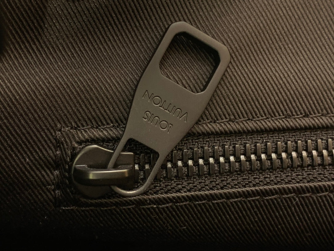 Close-up of zipper pull on textured fabric with embossed logo tab