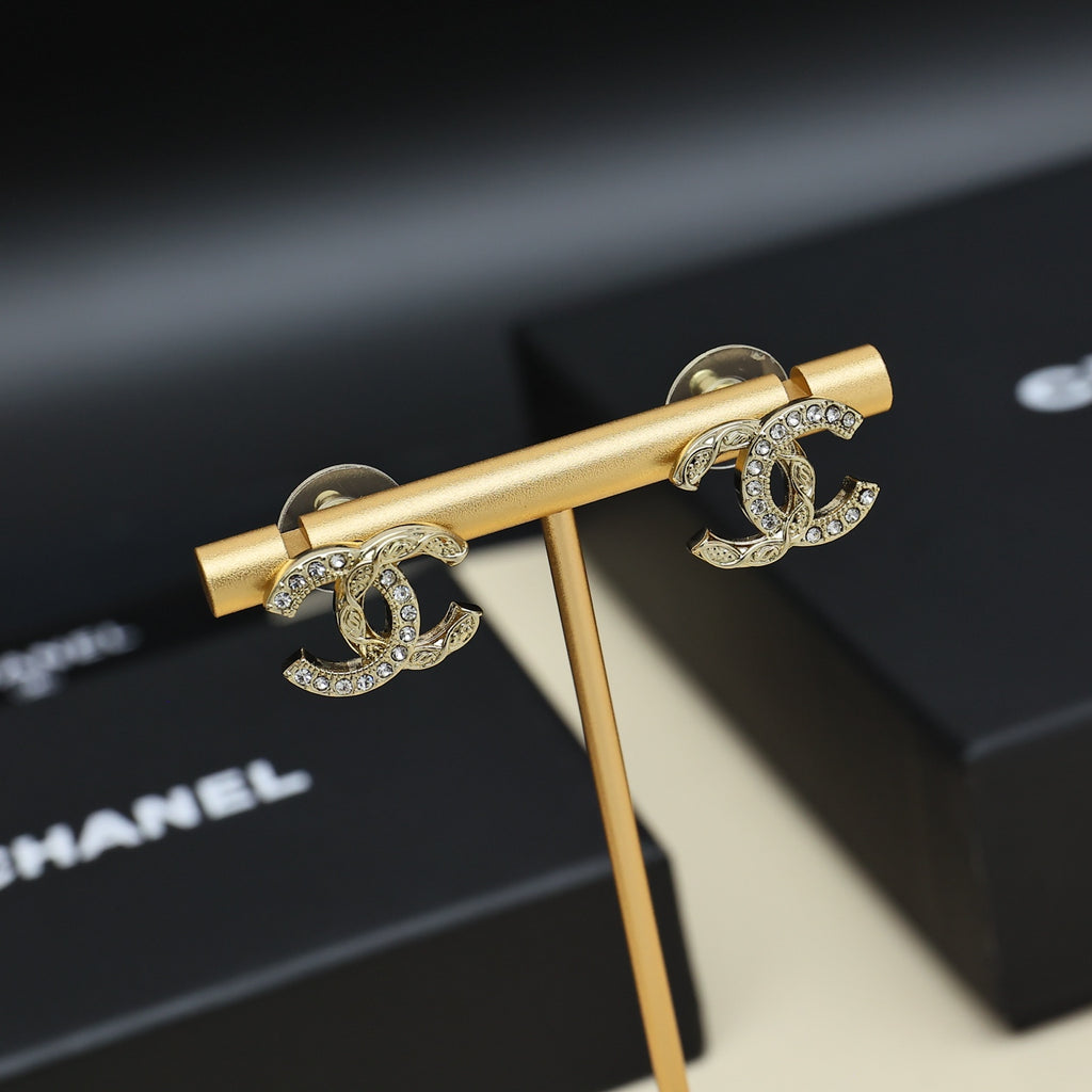 Gold-tone CC earrings with rhinestones on a gold-tone display