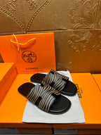 Black slide sandals with zebra-striped straps, front-facing on white dust bag.
