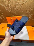 Blue patterned slide sandals on dust bag, side view