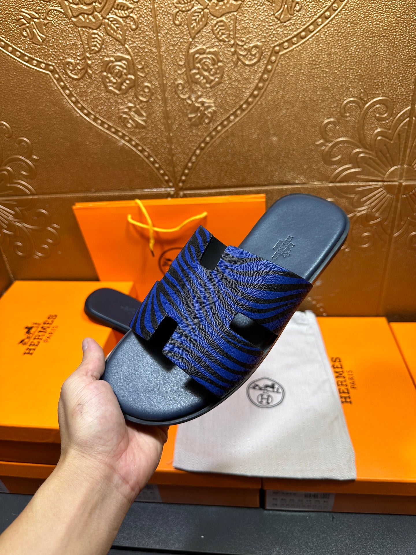 Blue patterned slide sandals on dust bag, side view