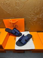 Blue patterned slide sandals held in hand, black strap detail