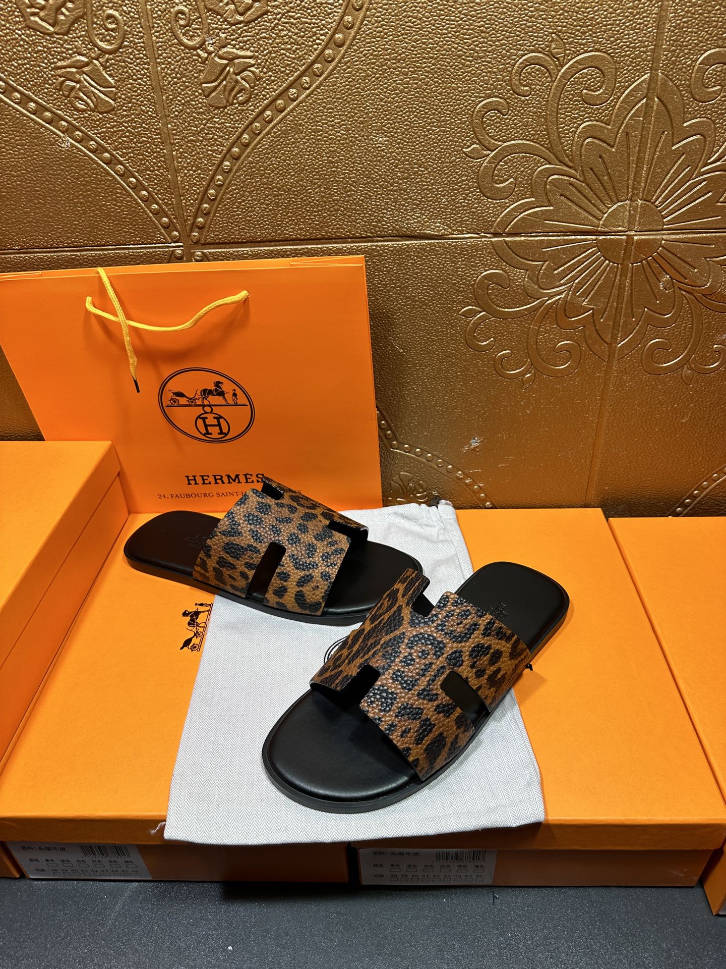 Leopard-print slide sandals with black footbed, angled view over a white dust bag.