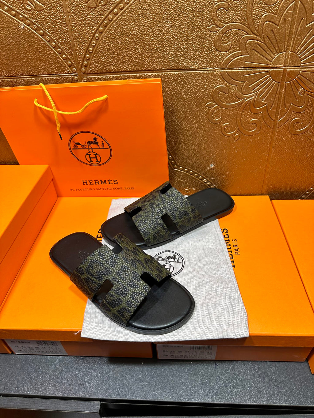 Hermes luxury slide sandals, dark patterned straps on black footbed