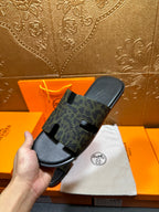 Hermes luxury slide sandals, dark patterned strap and black sole on hand