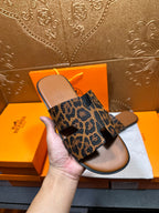 Hermes leopard-print slide sandals held up, wide straps visible