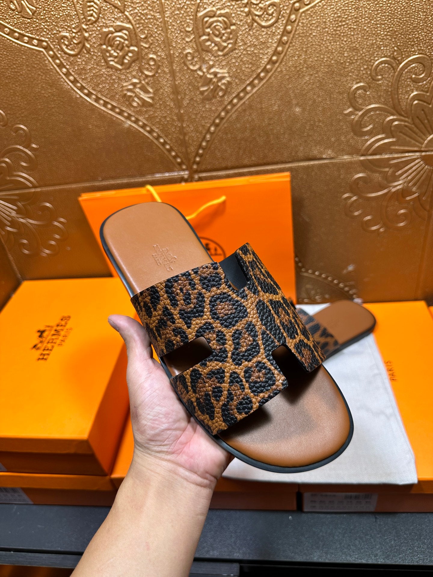 Hermes leopard-print slide sandals held up, wide straps visible