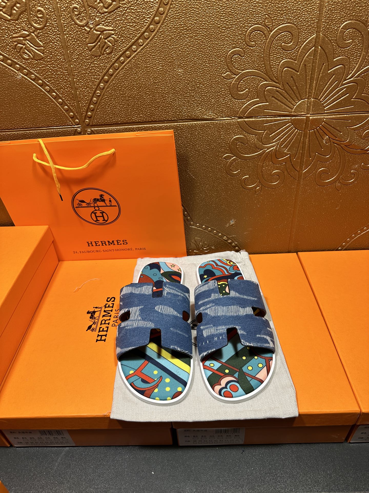Blue denim slide sandals with colorful patterned footbed and adjustable strap