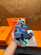Blue slide sandals with patterned footbed and denim strap detail in hand