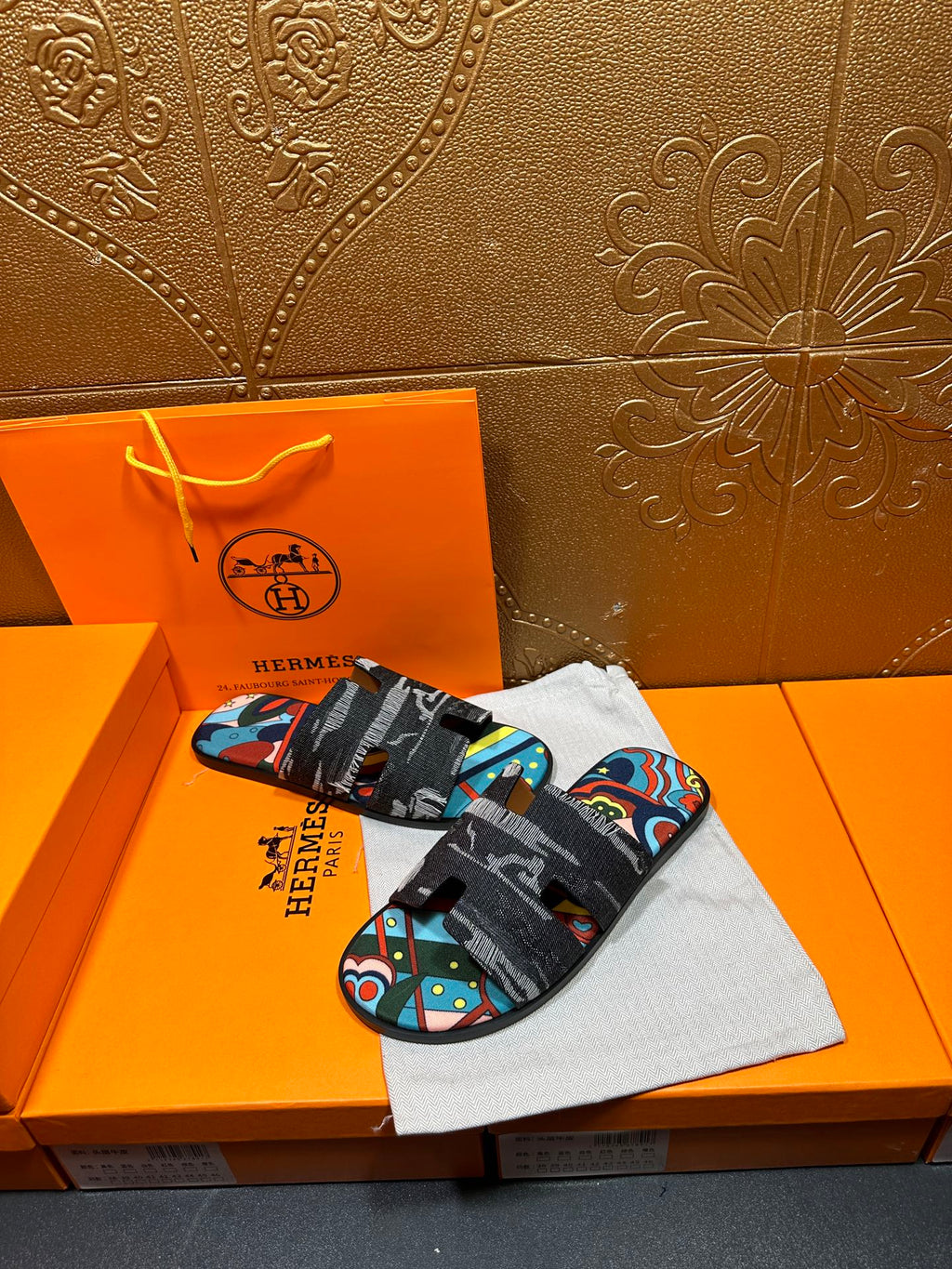 Hermes sandals with black straps and bright abstract print across the top
