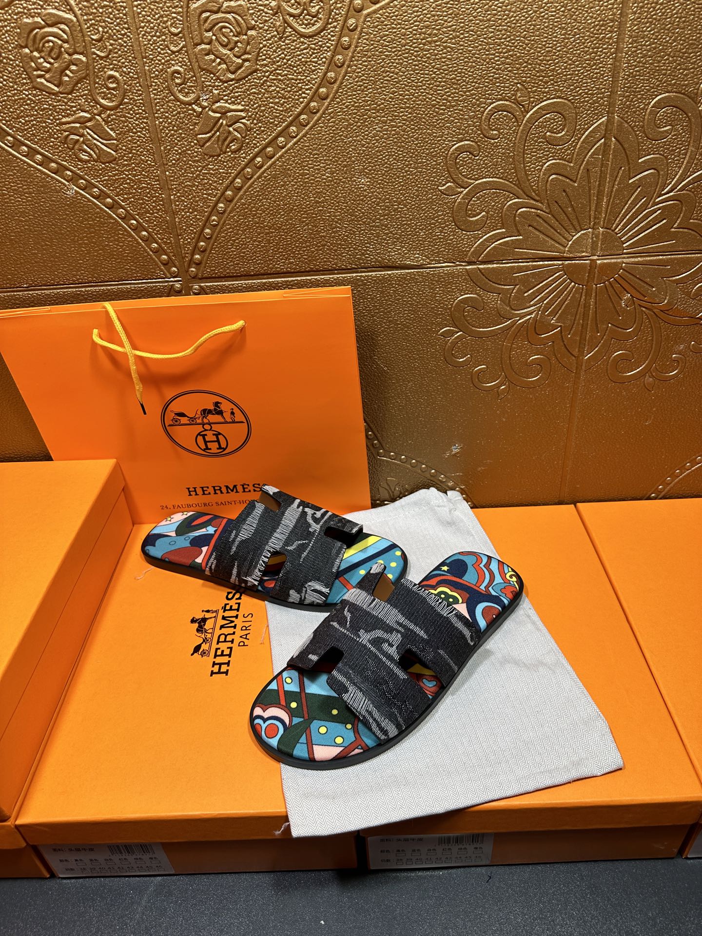 Hermes sandals with black straps and bright abstract print across the top