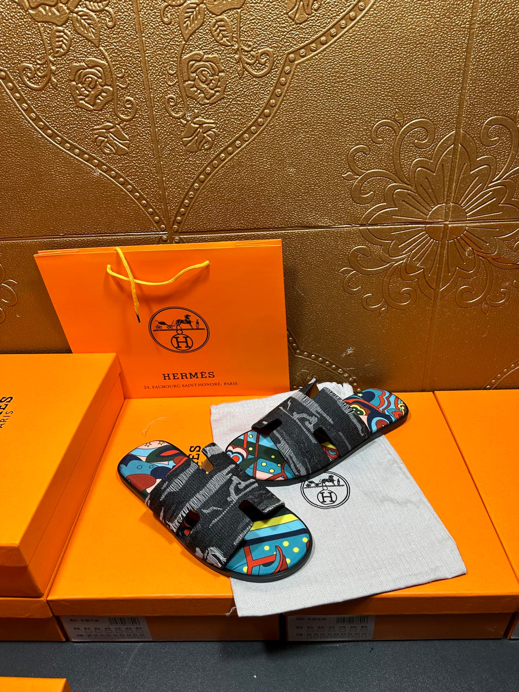 Hermes slide sandals with black strap and colorful abstract pattern on the upper