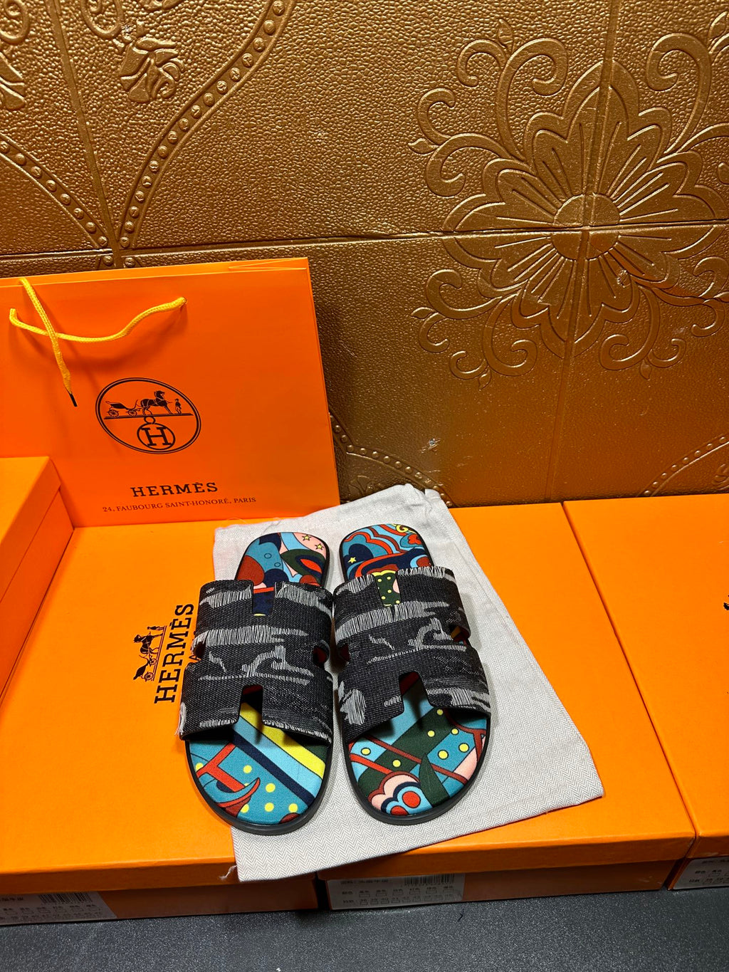 Hermes slide sandals with black straps and colorful abstract print footbed