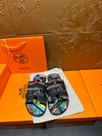 Hermes slide sandals with black straps and colorful abstract print footbed