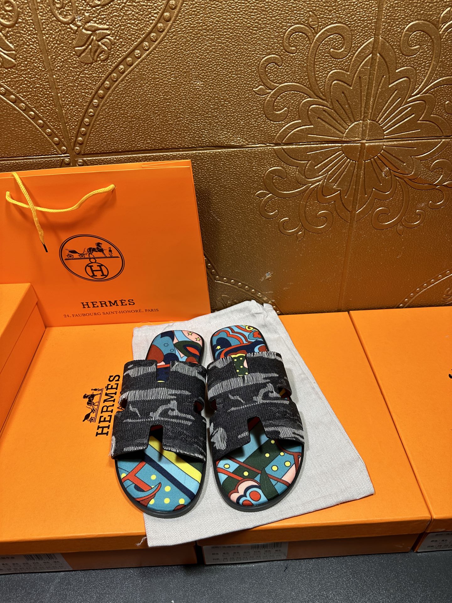 Hermes slide sandals with black straps and colorful abstract print footbed