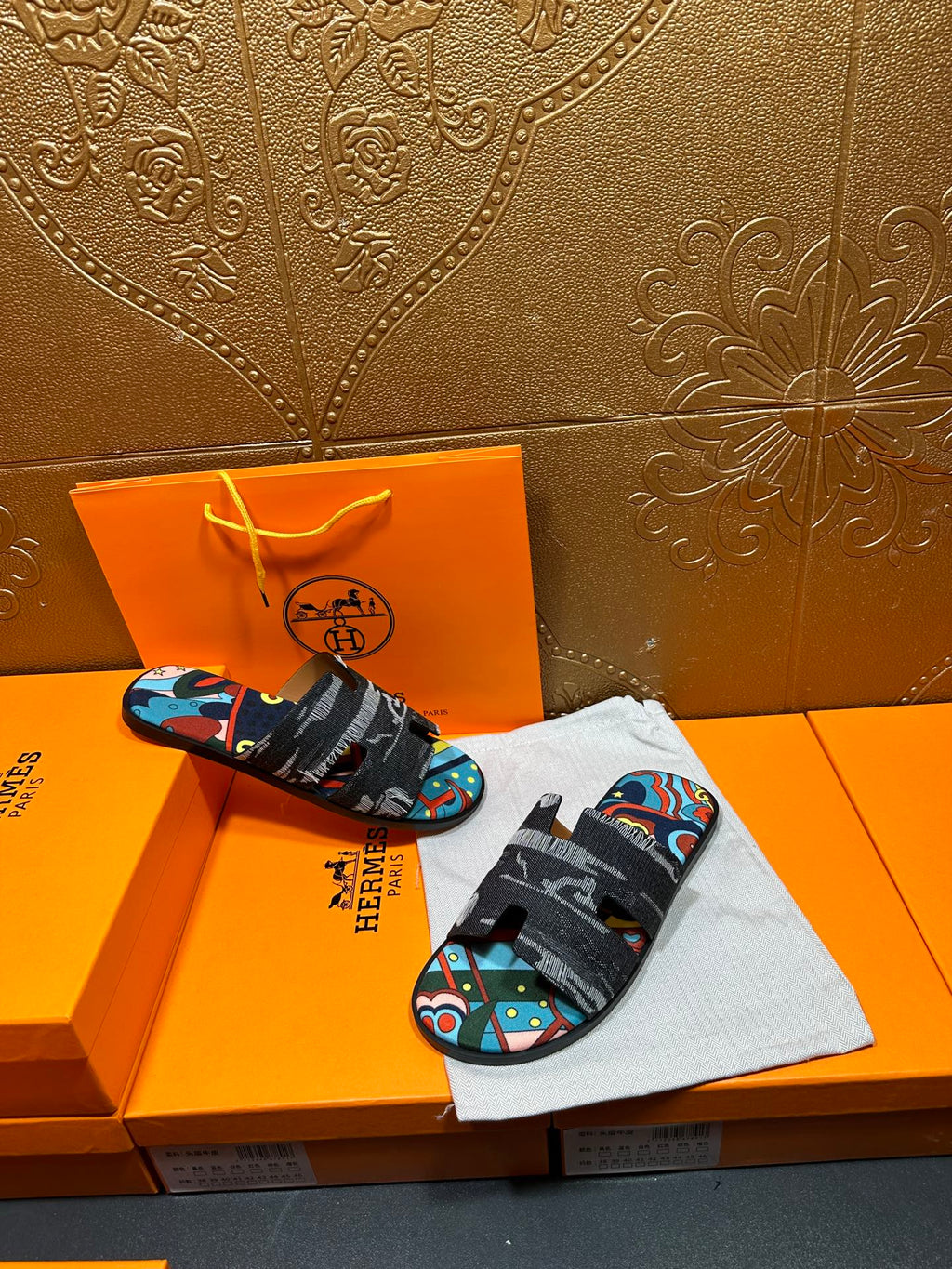 Hermes sandals displayed with black straps and multicolor abstract print footbed