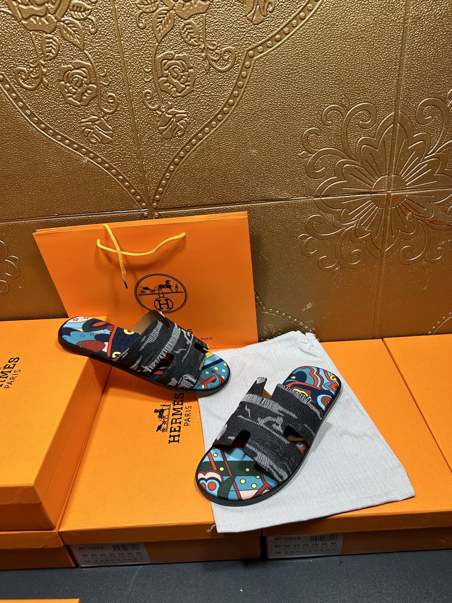 Hermes sandals displayed with black straps and multicolor abstract print footbed