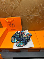 Two blue patterned sandals on cloth with frayed ankle wrap and toe strap
