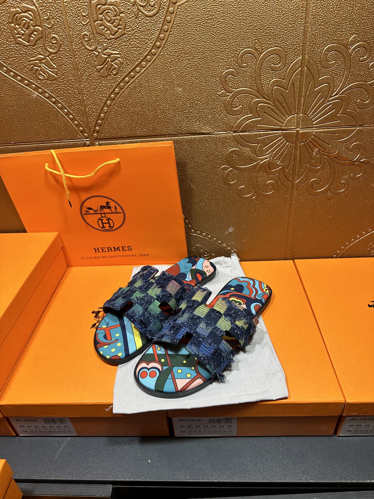 Two blue patterned sandals on cloth with frayed ankle wrap and toe strap