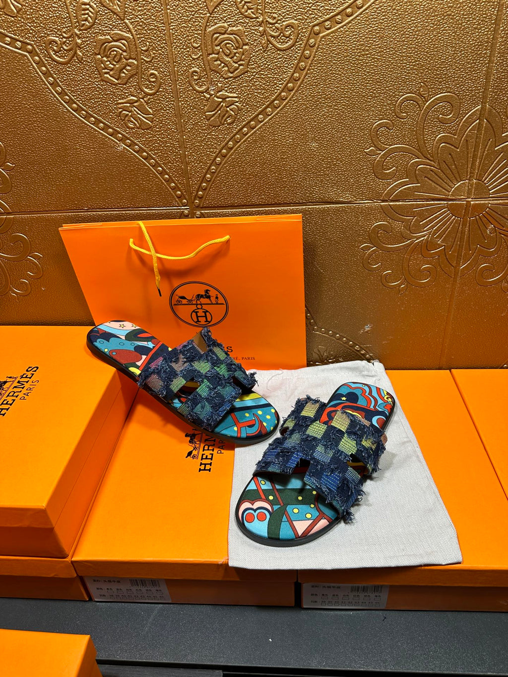 Pair of blue patterned slide sandals with multicolor footbed and frayed ankle wrap
