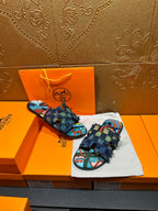 Pair of blue patterned slide sandals with multicolor footbed and frayed ankle wrap