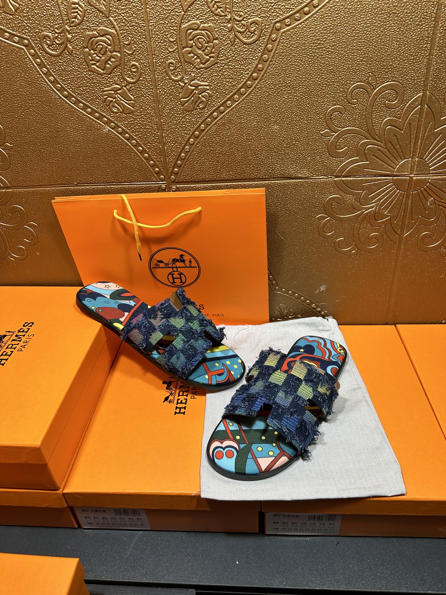Pair of blue patterned slide sandals with multicolor footbed and frayed ankle wrap