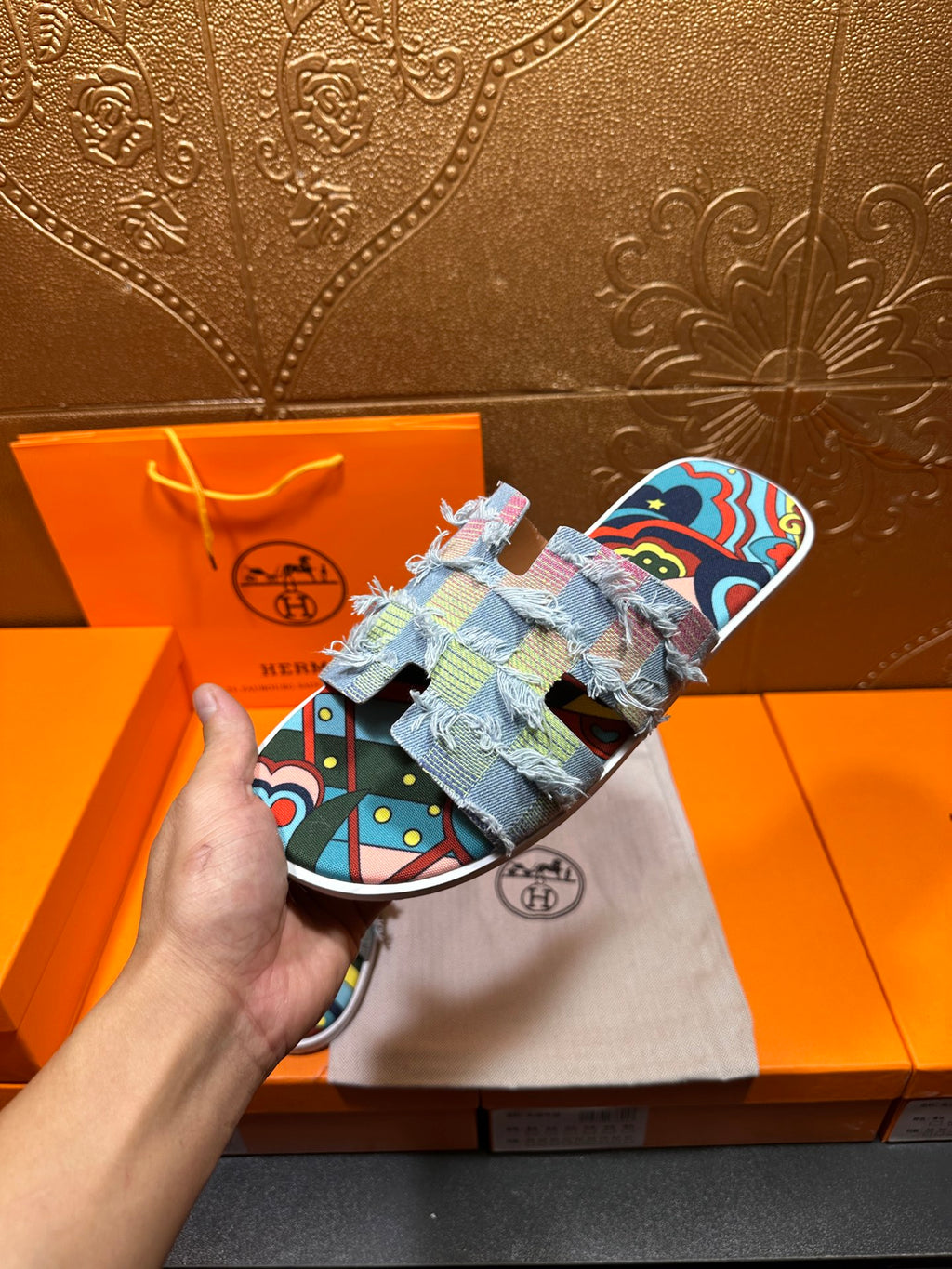 Hermes patchwork slide sandals held up, multicolor fabric straps and light blue patterned sole