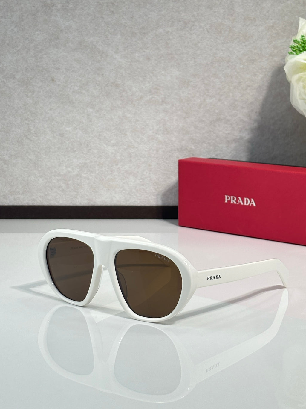 Prada oversized cat-eye sunglasses with white frames and brown-tinted lenses
