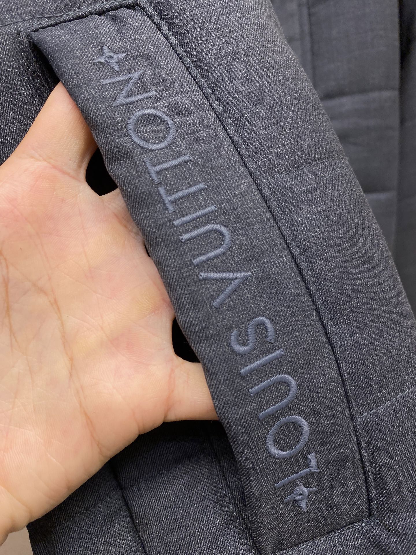 Dark blue jacket strap with vertical Louis Vuitton text
