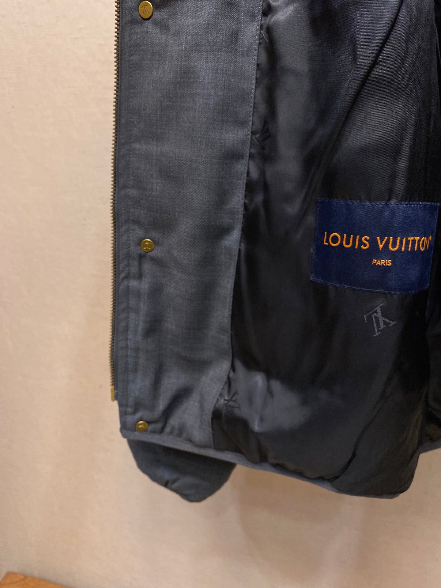 Dark blue jacket front with gold-tone snap buttons and inner brand patch