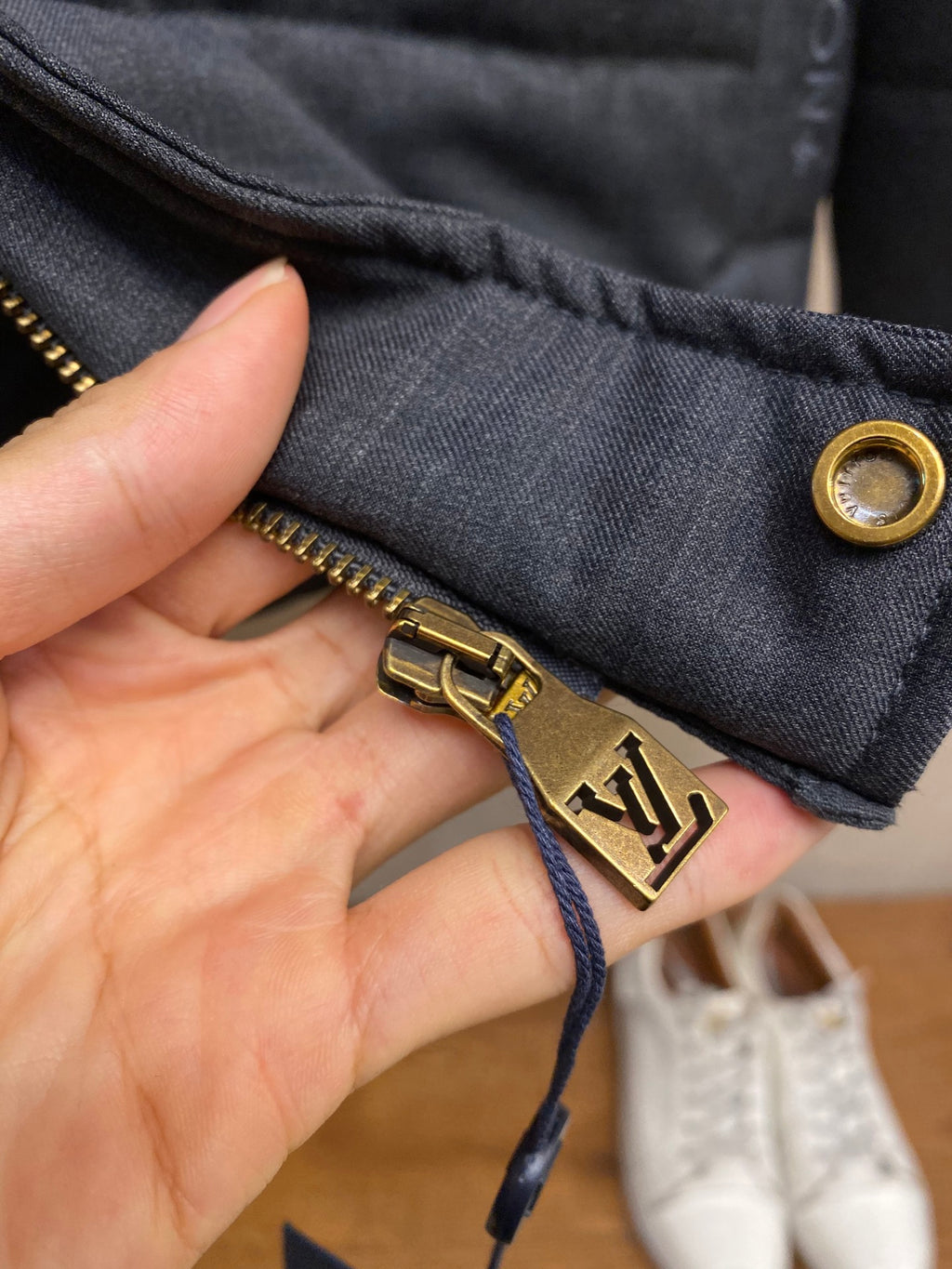 Dark blue jacket cuff with gold-tone button and zipper detail