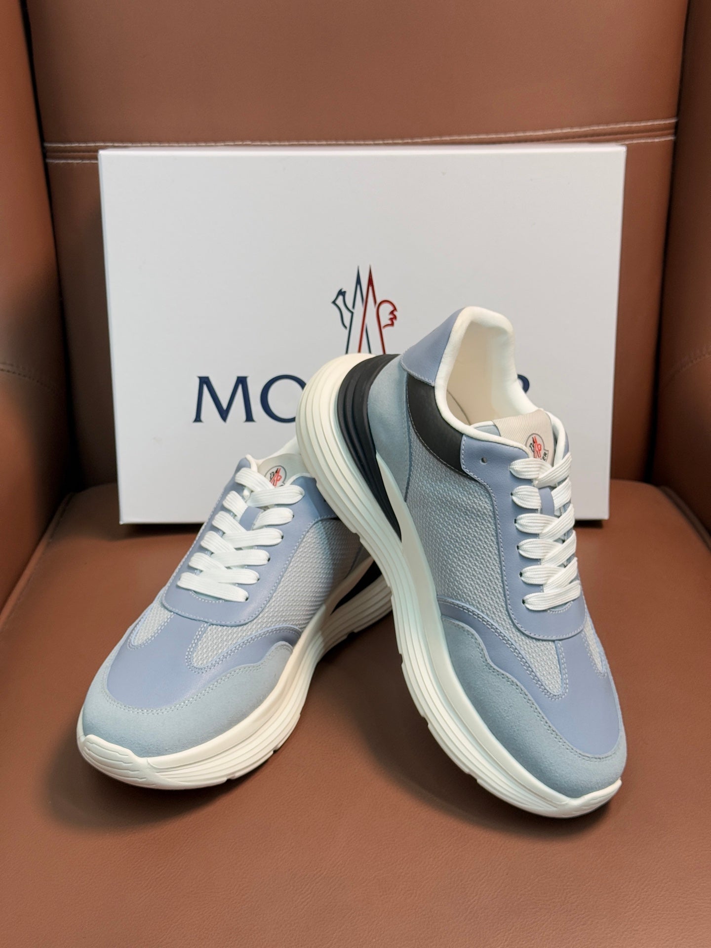 Light blue Moncler sneakers with white laces, stacked heel look, dark collar trim