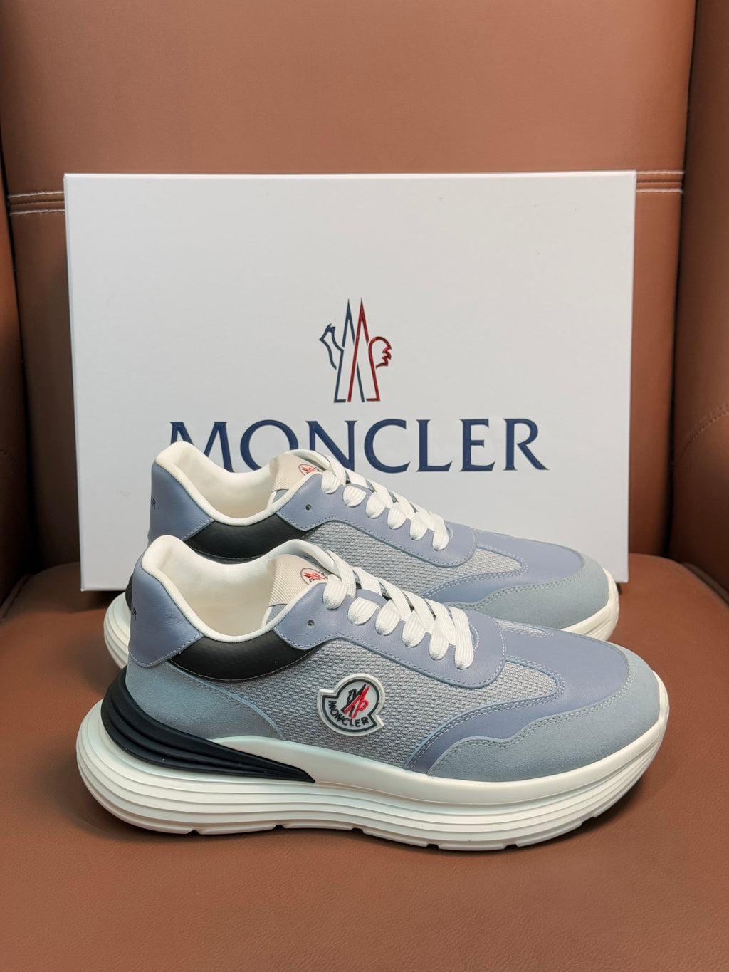 Pair of light blue Moncler sneakers with white laces, cushioned sole, side logo patch
