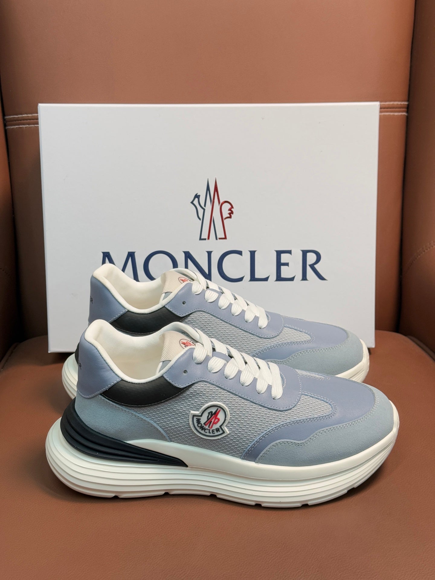 Pair of light blue Moncler sneakers with white laces, cushioned sole, side logo patch