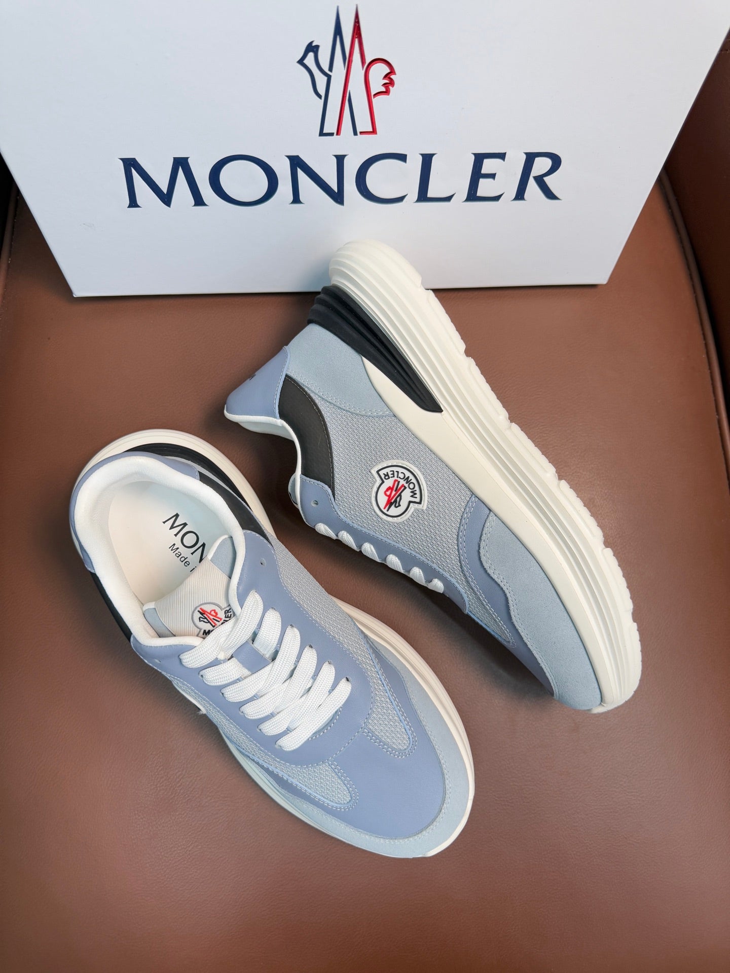 Light blue Moncler sneakers with side patch detail, black accents, off-white sole