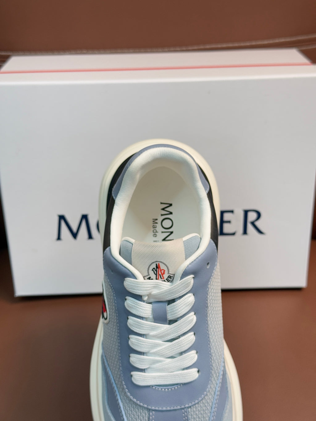 Light blue Moncler sneaker front close-up with white laces and 'MONCLER' on tongue