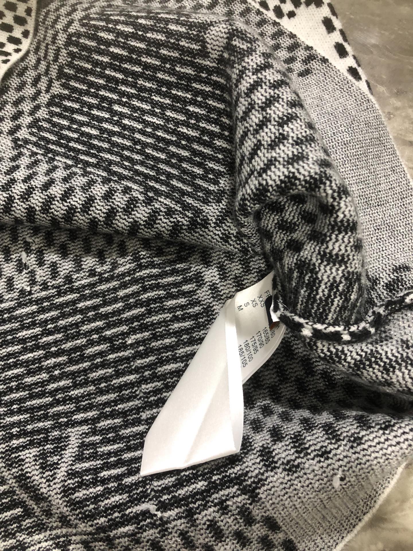Knitted sleeve and cuff detail in black-and-white check texture