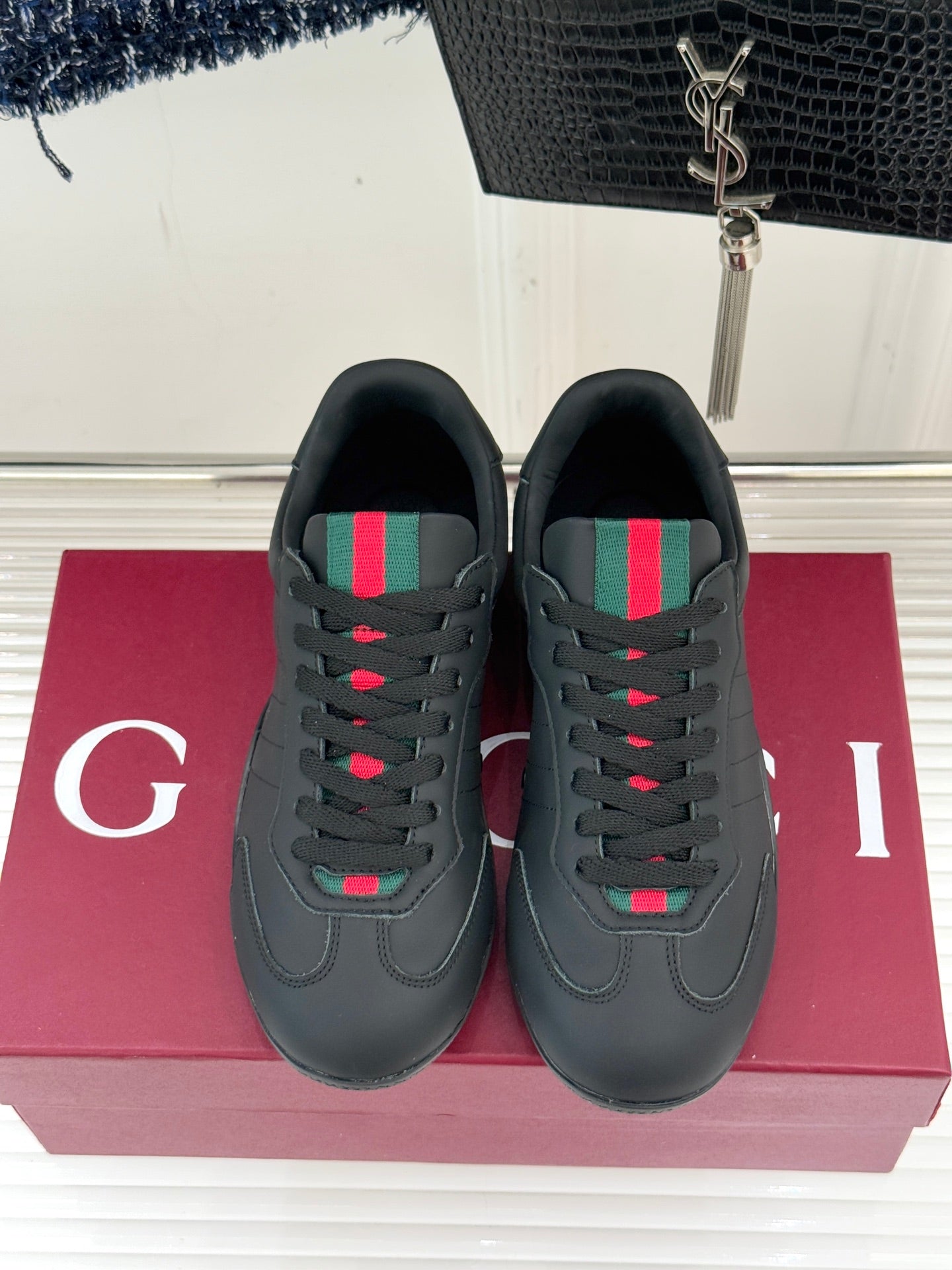 Black leather sneakers facing front with multicolor stripe detail on the tongue area