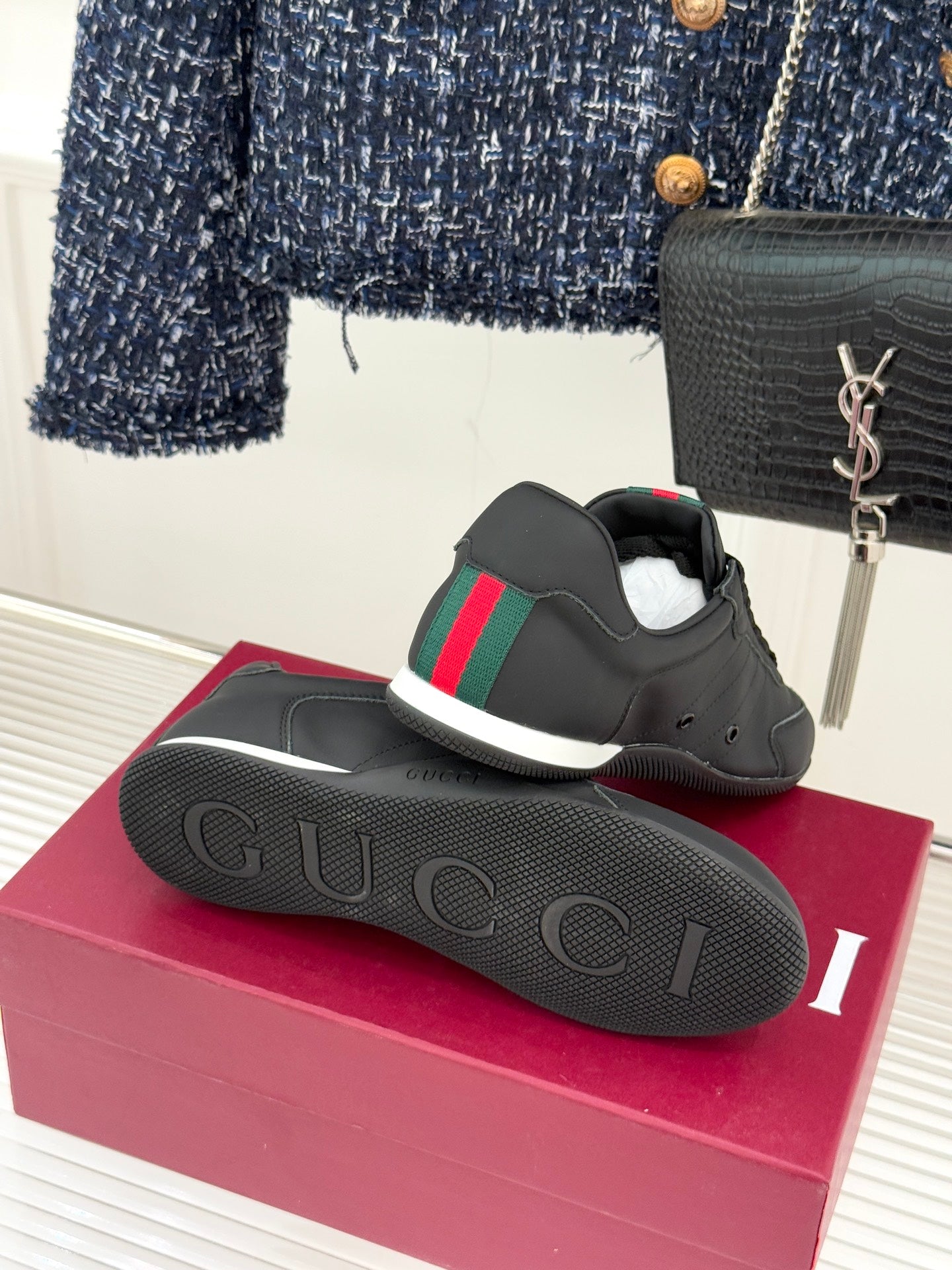 Black leather sneaker and outsole on a box, featuring red and green stripe accents