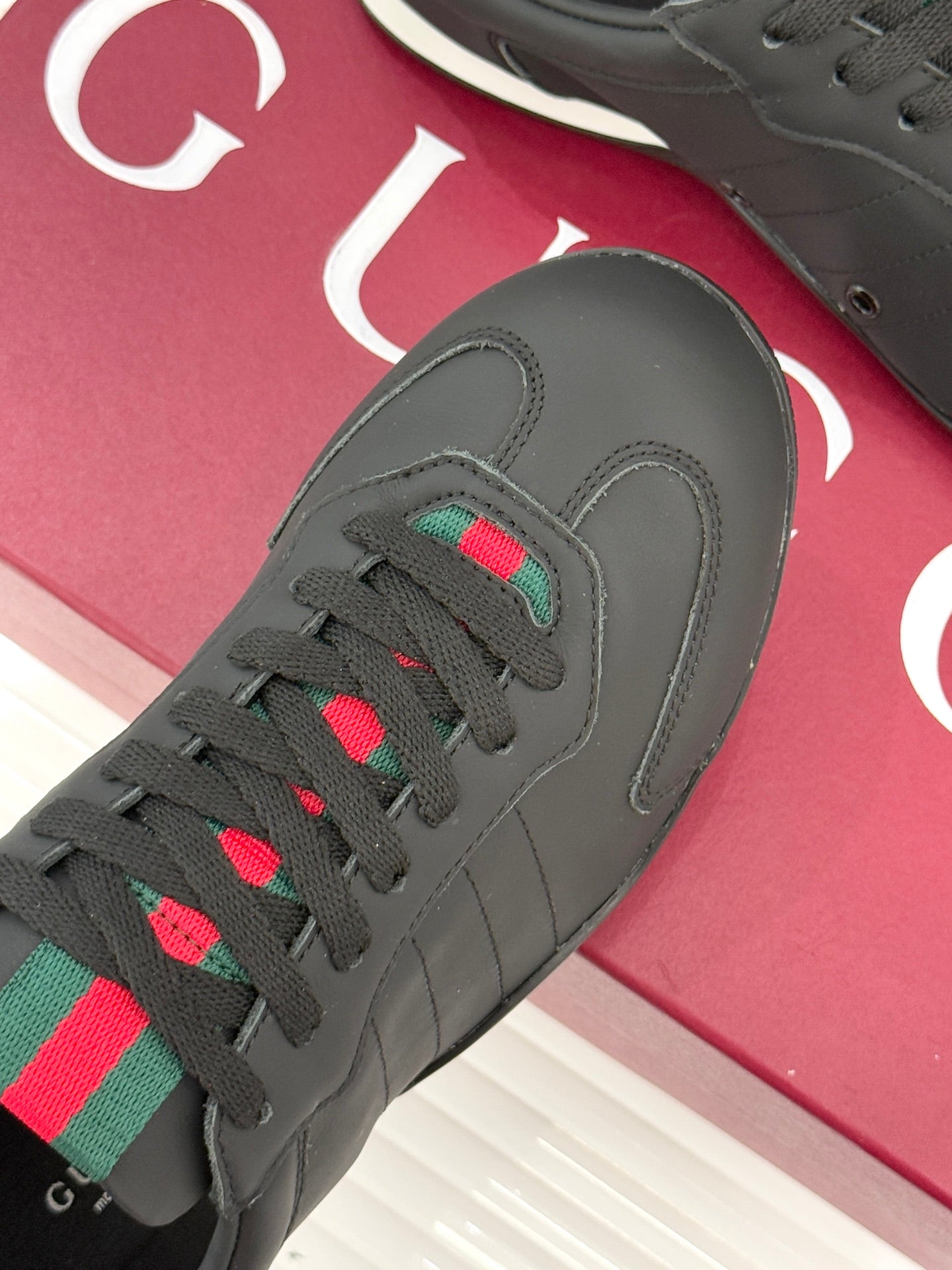 Close-up of black sneaker upper with multicolor stripe patch on the lace area