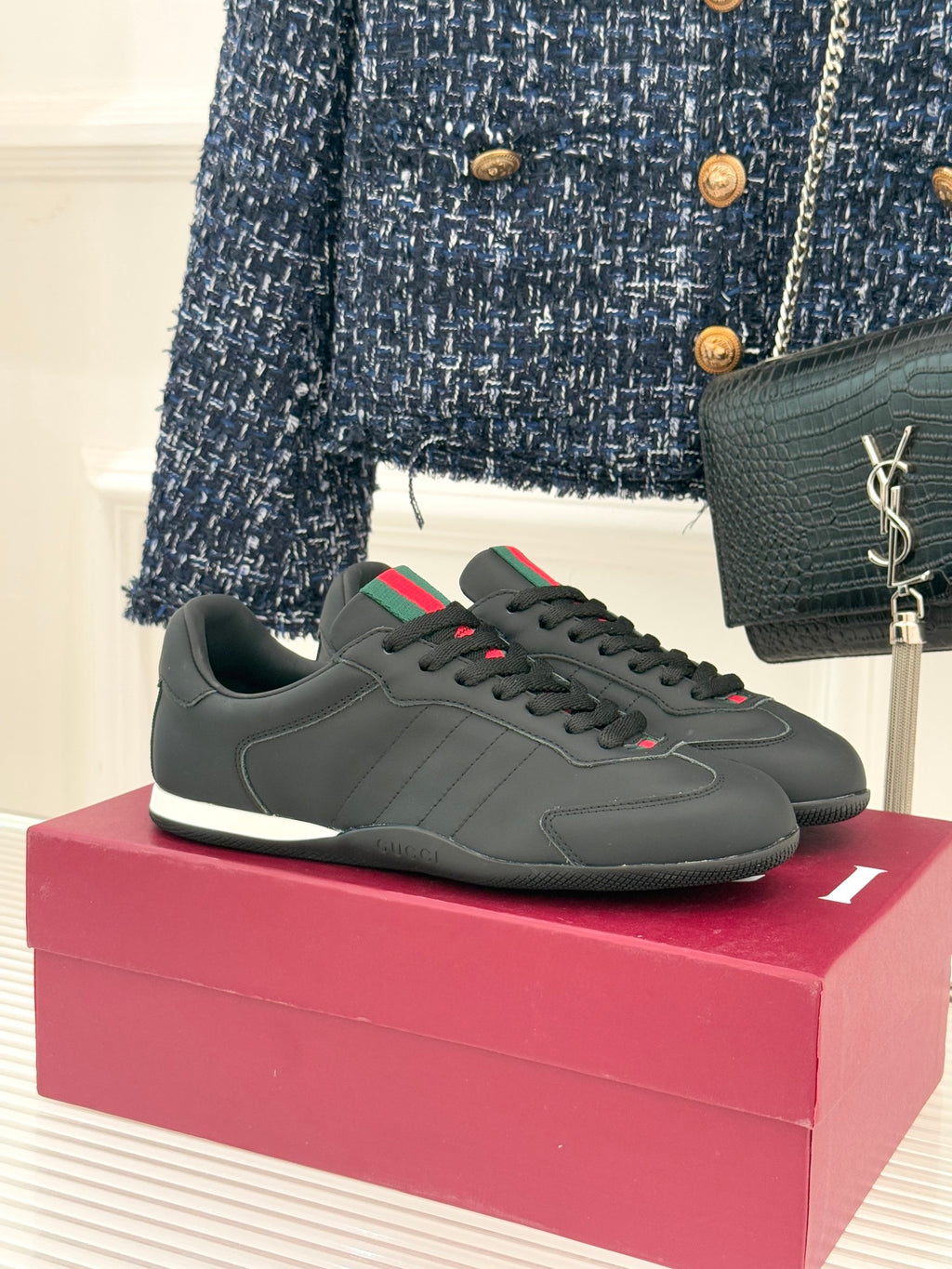 Black leather low-top sneaker with red and green stripe detail and white sole