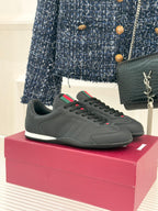 Black leather low-top sneaker with red and green stripe detail and white sole