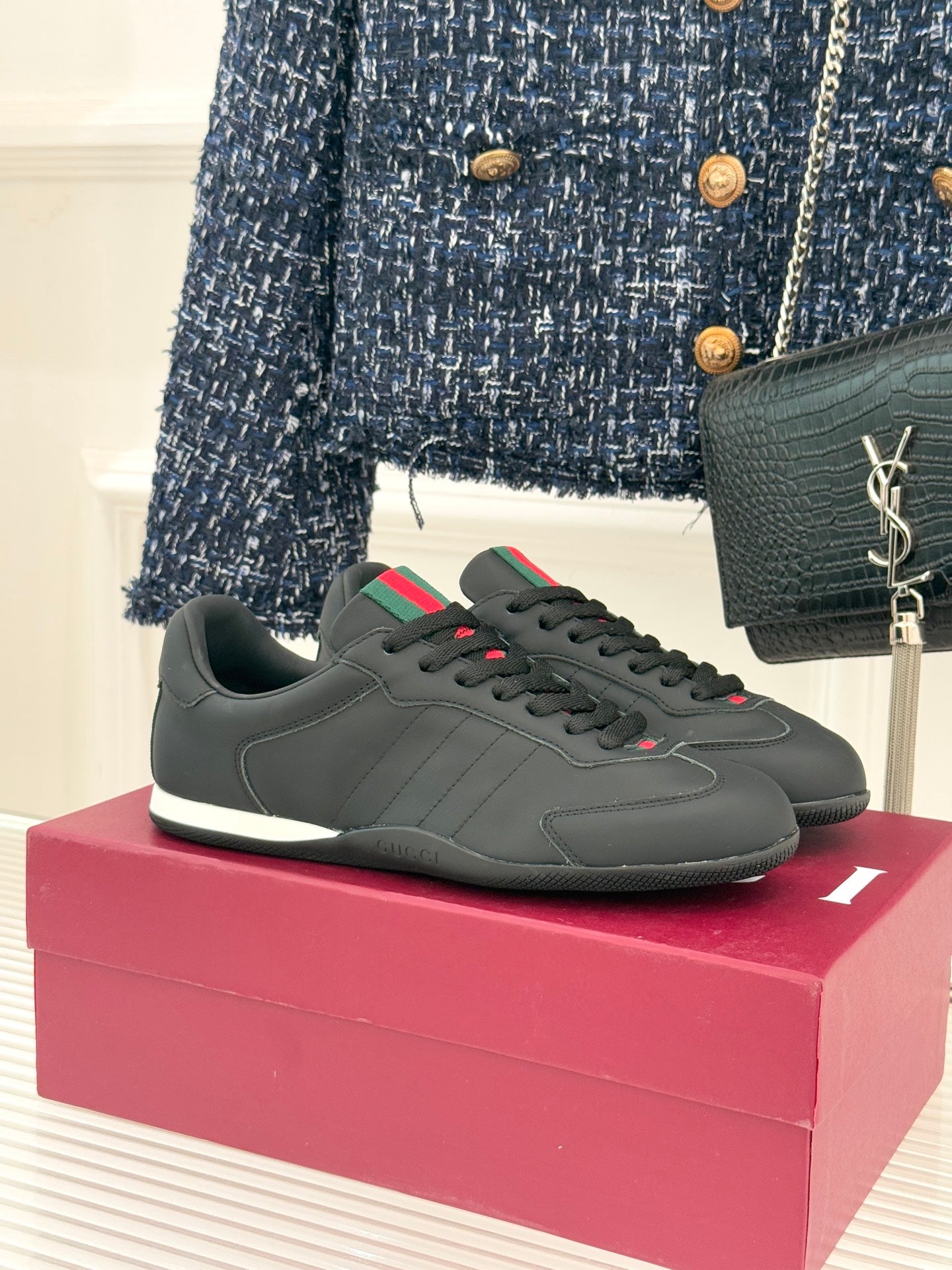 Black leather low-top sneaker with red and green stripe detail and white sole