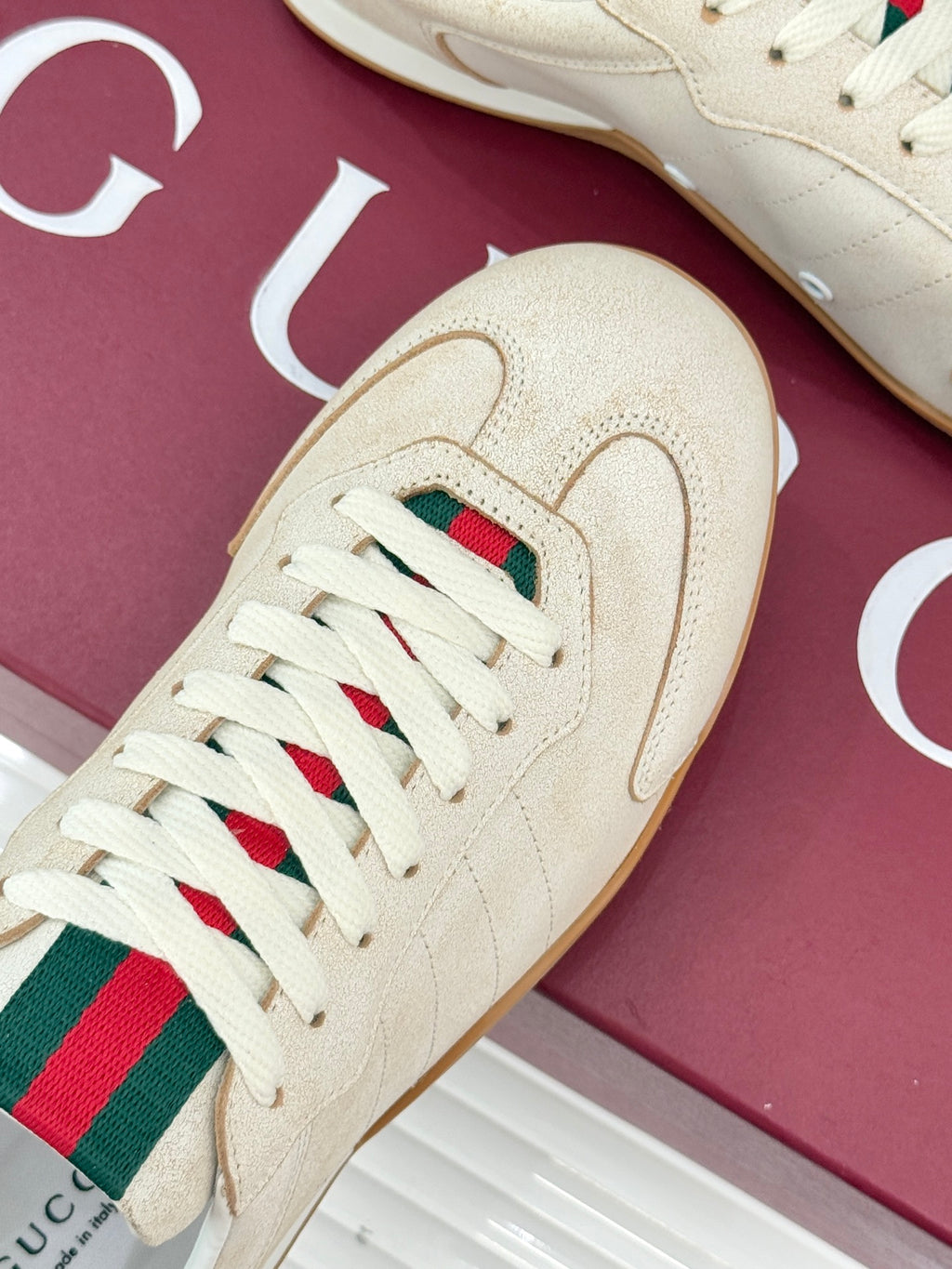 Cream sneaker with green-red web stripe on tongue, white laces